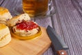 Scones traditional English delicious freshly baked homemade with strawberry jam on a wooden cutting board with a knife. Royalty Free Stock Photo