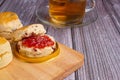 Scones traditional English delicious freshly baked homemade with strawberry jam on a wooden cutting board on a wood table. Royalty Free Stock Photo