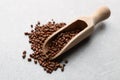 Scoop with buckwheat tea granules on light grey table, closeup