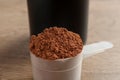 Scoop of chocolate protein powder on wooden table Royalty Free Stock Photo