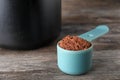 Scoop of chocolate protein powder on wooden table Royalty Free Stock Photo