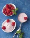 A scoop of homemade raspberry ice cream with fresh raspberries and mint in a white cup on a blue background. Delicious and Royalty Free Stock Photo