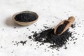 Scoop of Indian spice Black cumin nigella sativa or kalonji seeds on white table close up