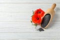 Scoop of poppy seeds and flowers on white wooden table, flat lay Royalty Free Stock Photo