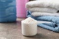 Scoop with powder on gray table with towels and bottles