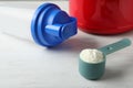 Scoop of protein powder and sports bottle on white wooden table Royalty Free Stock Photo