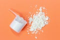 Scoop with scattered protein powder, side view on orange background Royalty Free Stock Photo