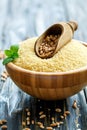 Scoop with wheat in a wooden bowl with couscous.