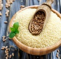 Scoop with wheat in a wooden bowl with couscous.