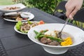 Scooping up Beef Bulalo. Filipino food with Dinakdakan, Chop Suey, and Stuffed Bangus. Outdoor garden setting