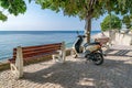 A scooter next to a bench and a tree with the see in the background. Travel and adventure concept. A scooter travel and adventure