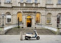 Scooter parked by the steps of an old stone building