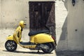 Scooter Yellow Motorcycle In Front Of Old Houses With White Wall