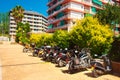 Scooters and motorcycles in parking lot near apartment building on the street in Lloret de Mar, Costa Brava, Spain