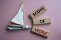 Scope of Work symbol. Concept words Scope of Work on wooden blocks. Beautiful pink background with boat. Business and Scope of