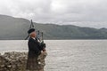 Scot playing bagpipes in front of the lake Royalty Free Stock Photo