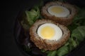 Scotch egg halved on lettuce leaves in a black dish. Royalty Free Stock Photo