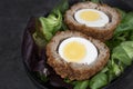 Scotch egg halved on lettuce leaves in a black dish. Royalty Free Stock Photo