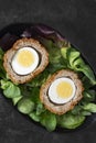 Scotch egg halved on lettuce leaves in a black dish. Royalty Free Stock Photo