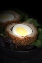 Scotch egg halved on lettuce leaves in a black dish. Royalty Free Stock Photo