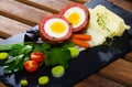 Scotch egg srved with mashed potatoes and greens, Scottish traditional dish