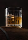 Scotch whiskey in crystal glass with ice cubes on wooden barrel and black Royalty Free Stock Photo