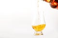 Scotch Whiskey without ice in glass pouring out of the bottle, white background, copy space