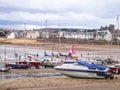 Scottish coastal scene with sailing sloops on beach at low tide.