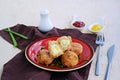 Scottish eggs, boiled quail eggs in minced chicken on a red clay plate on a light concrete background. Can be served as a starter