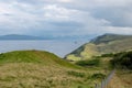 Scottish landscape with hills and shoreline near Staffin at Isle of Skye with green pastures and a fence protecting sheeps