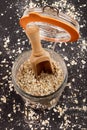 Scottish rolled oatmeal in a storage glass and wooden scoop