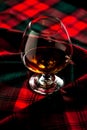 Scottish whiskey in a glass on tartan background