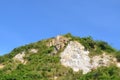 Scour mountain with green plant over blue sky
