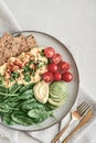 Scramble eggs with cherry tomatoes, fresh spinach leaves, avocado and crispbreads