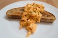 Scrambled egg served across a slice of buttered sourdough toast on a white plate Royalty Free Stock Photo