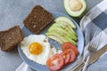 Scrambled eggs with avocado and tomato, whole grain bread, fork, knife, towel Royalty Free Stock Photo