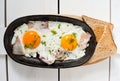 Scrambled eggs with bacon and fresh herbs fried in a pan. Served with bread toast Royalty Free Stock Photo