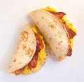 Scrambled eggs and bacon stuffed in tortillas shells on white background
