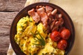 Scrambled eggs with chives, bacon and tomatoes close-up. horizon Royalty Free Stock Photo