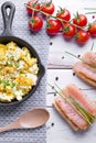 Scrambled eggs with chives in a cast iron pan, toasts with salmon and chives, and tomatoes. Healthy breakfasts on an old wooden wh Royalty Free Stock Photo