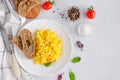 Scrambled eggs cooking from organic fresh eggs on a white plate with rye bread on a light background with a cup of coffee. Royalty Free Stock Photo