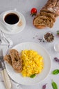 Scrambled eggs cooking from organic fresh eggs on a white plate with rye bread on a light background with a cup of coffee. Royalty Free Stock Photo