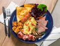 Scrambled eggs with fried bacon,ham,fried sausages,fries,mushroom, tomato and toast Royalty Free Stock Photo