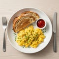Scrambled eggs garnished with chopped chives and black pepper sit on a white plate alongside slices Royalty Free Stock Photo
