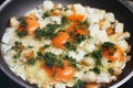 Scrambled eggs with mini toasts, greens and cheese on frying pan. Cooking process.