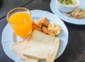 Scrambled eggs with pork sausages, bread and orange juice
