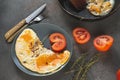 Scrambled eggs with tomato on a plate , knife and fork on a gray Royalty Free Stock Photo