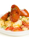Scrambled eggs with tomatoes and chorizo sausage on white background