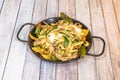 Scrambled eggs with vegetables, zucchini, peppers, mushrooms and homemade chips in black enameled paella pan Royalty Free Stock Photo