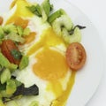 Scrambled eggs on a white plate, with salad of sliced avocado, cherry tomatoes, green celery, fresh coriander and basil Royalty Free Stock Photo